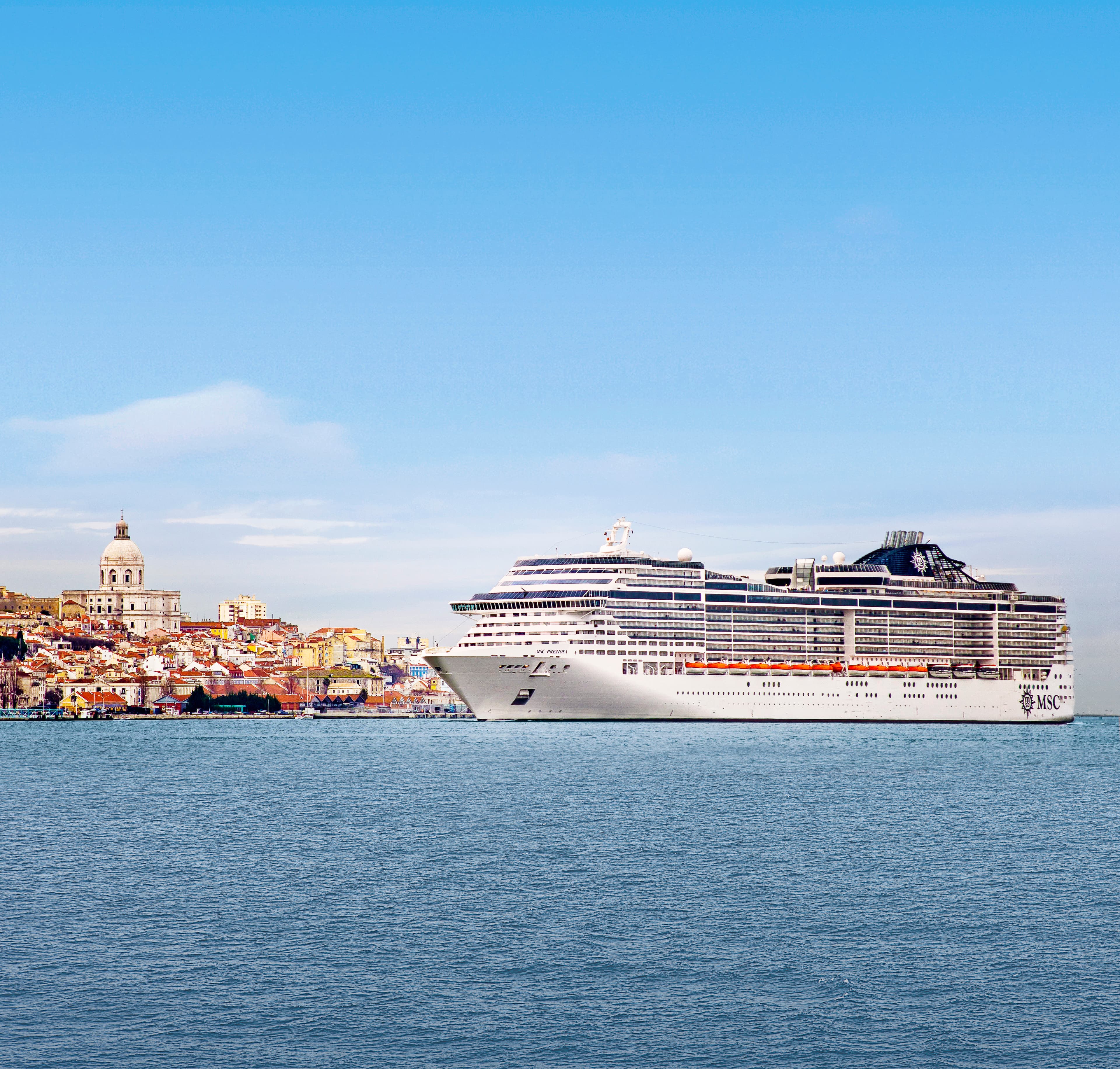 MSC Preziosa sunny exterior profile at sea with Lisbon hillside behind
